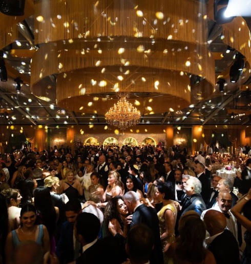 A wedding reception hall filled with guests under chandelier light
