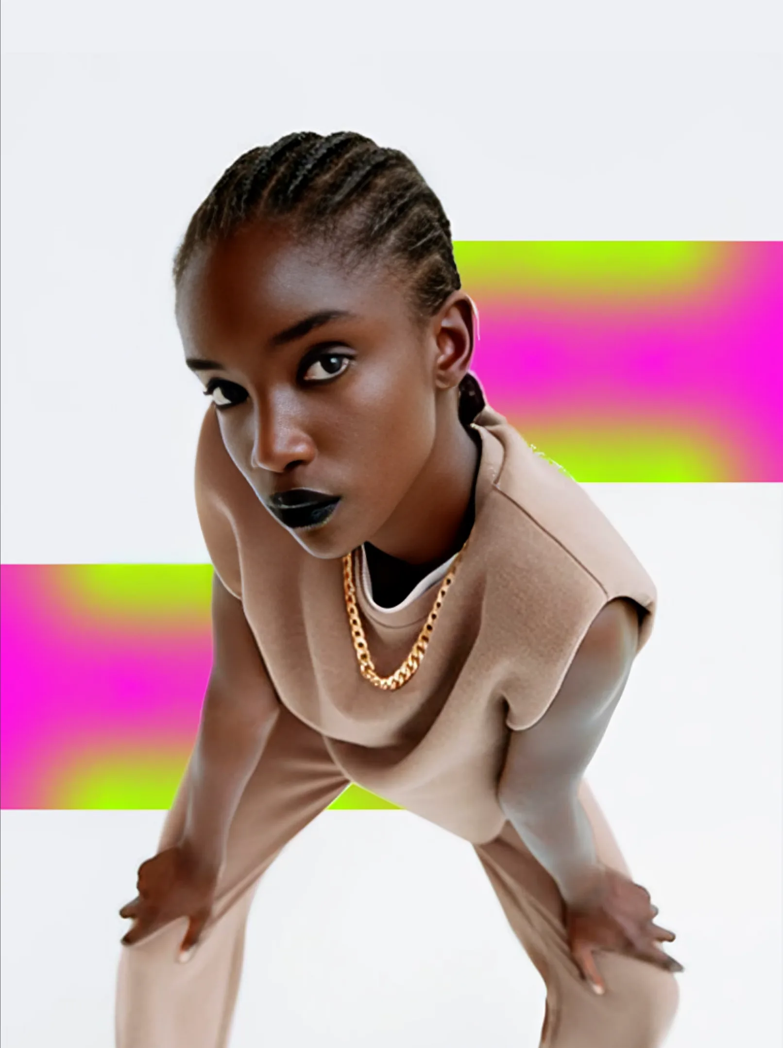 A model in a sculpted beige top against neon pink and green blocks.