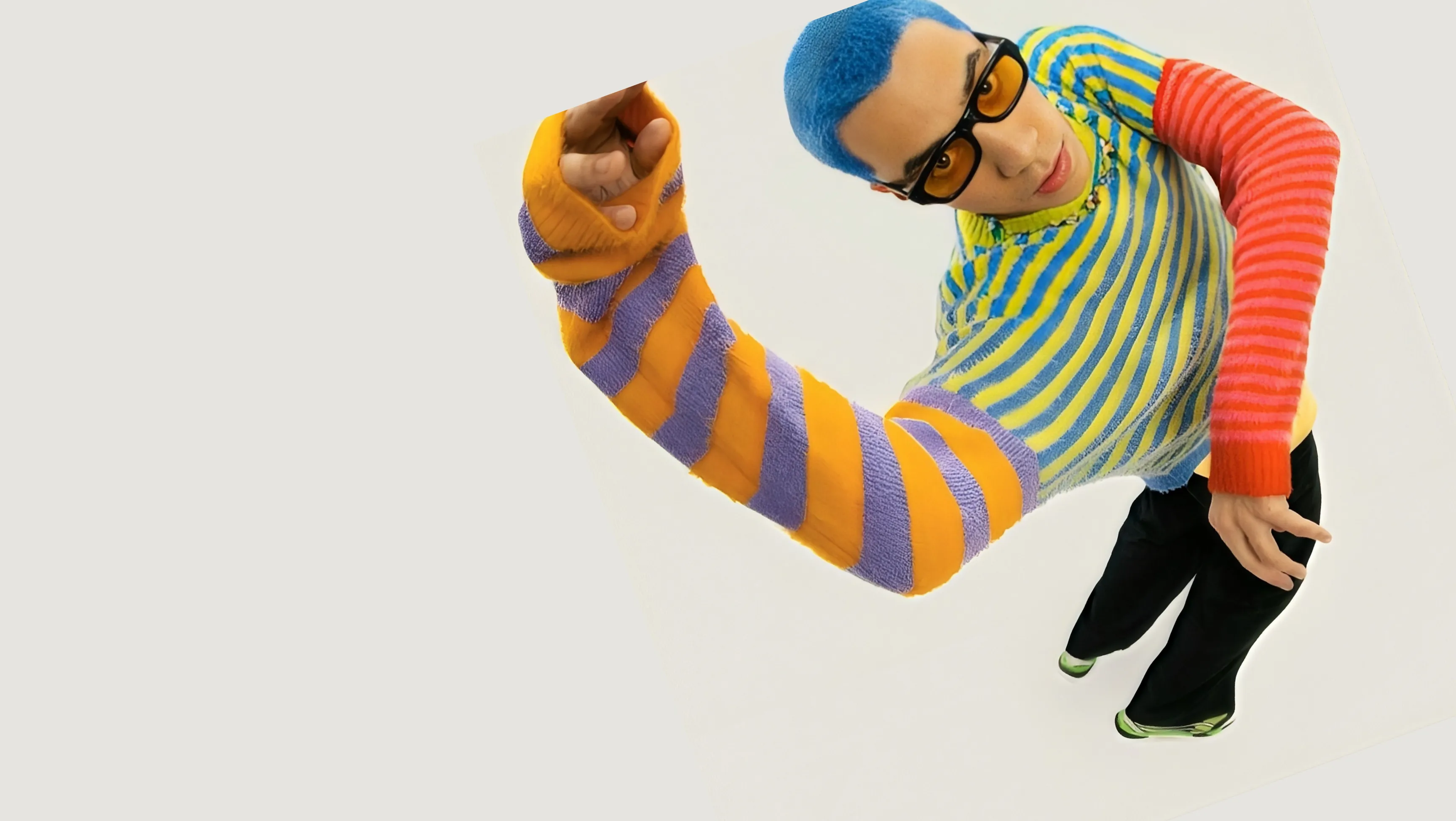 A model with blue hair in a striped jumper, one arm stretched towards the camera.