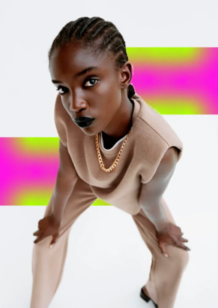 A model in a sculpted beige top against neon blocks.