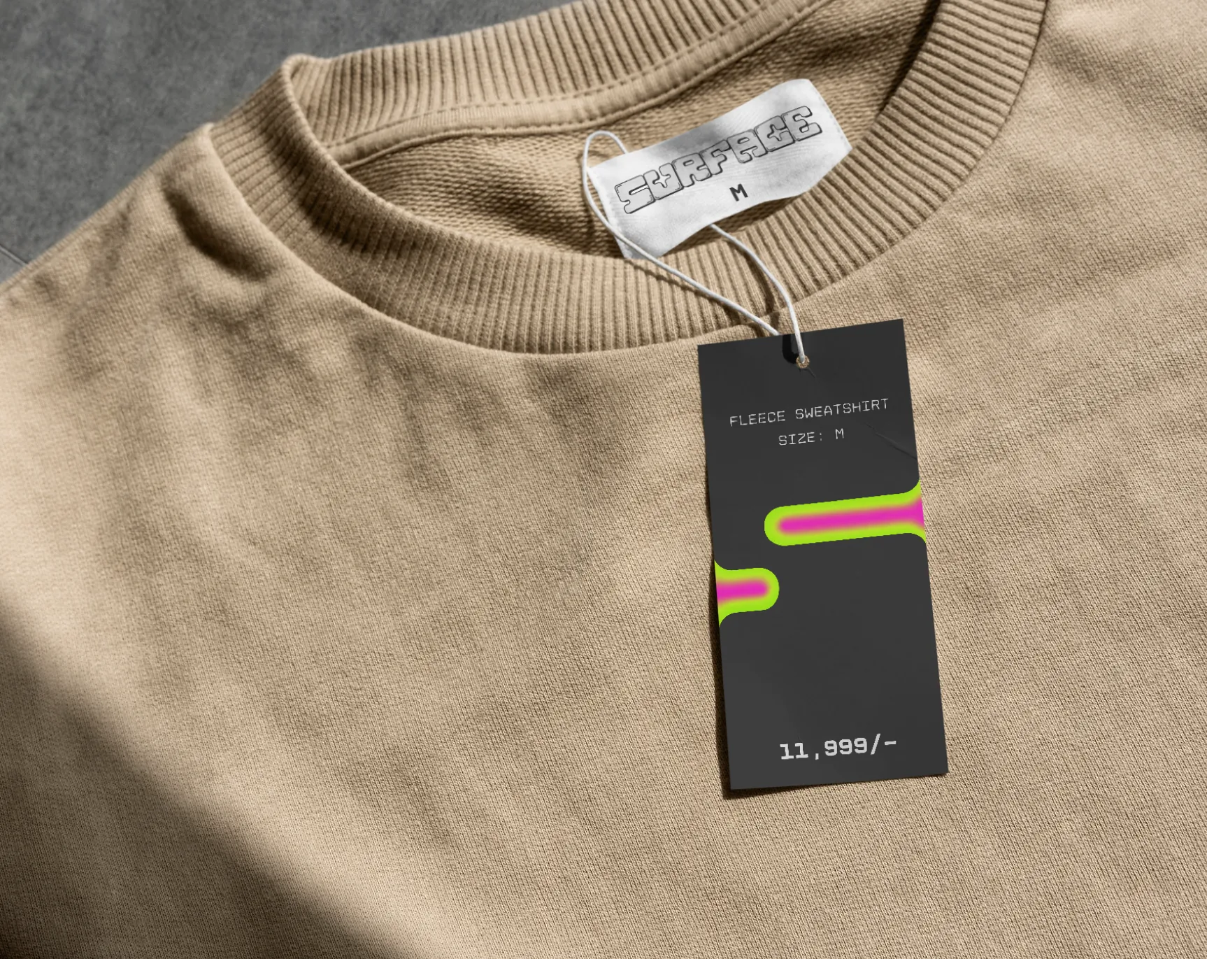 A Surface swing tag hanging off a beige sweatshirt’s collar.